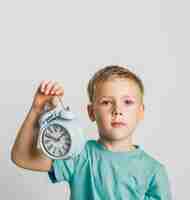 Free photo front view cute kid holding a clock