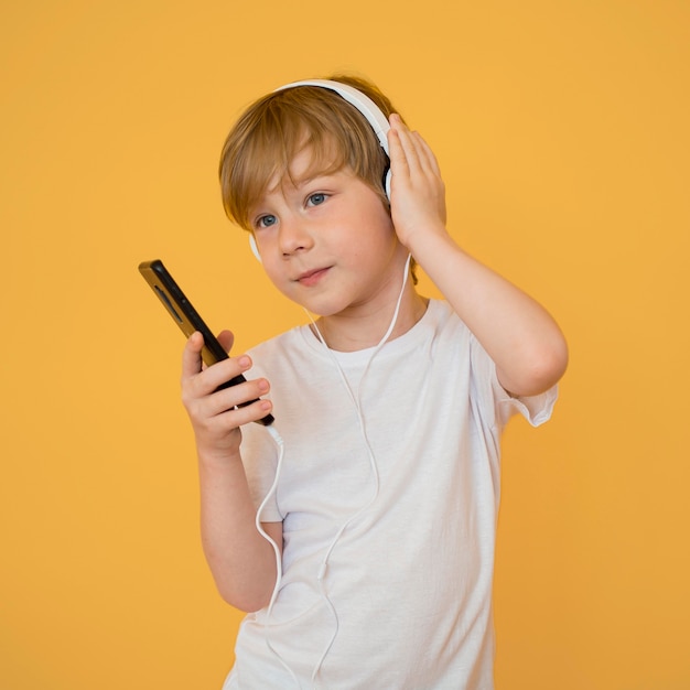 Front view of cute little boy listening to music