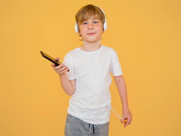 Front view of cute little boy listening to music