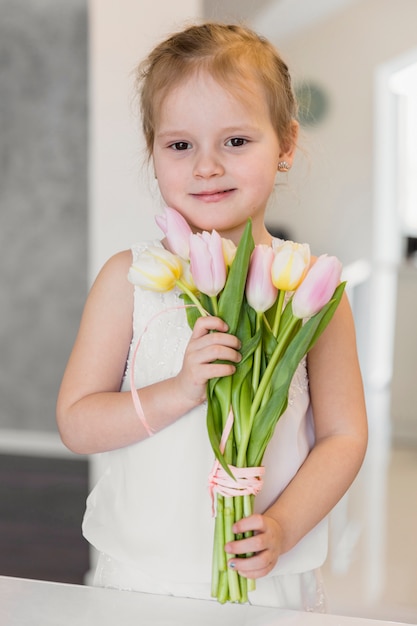 Front view of cute little girl holding tulip flowers bunch