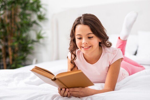 Вид спереди милая маленькая девочка читает рассказы