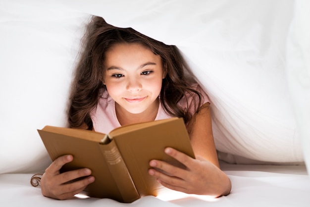Вид спереди милое чтение маленькой девочки
