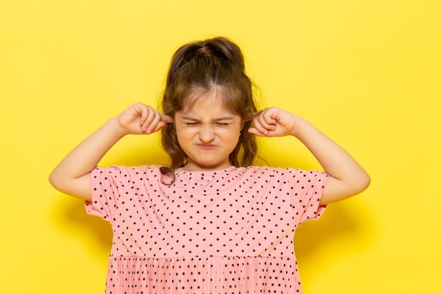 彼女の耳を覆うピンクのドレスで正面のかわいい子供