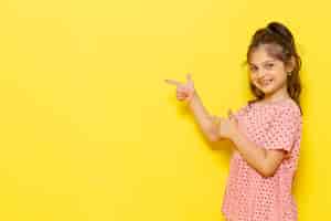 Free photo a front view cute little kid in pink dress smiling and pointing out