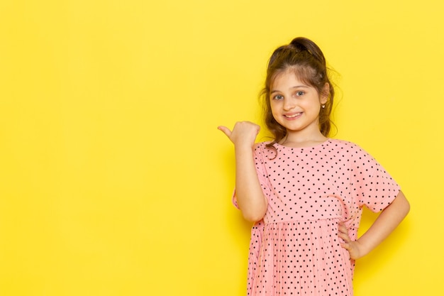 A front view cute little kid in pink dress smiling and posing