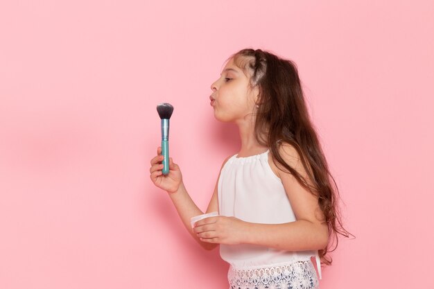 A front view cute little kid preparing to do make-up