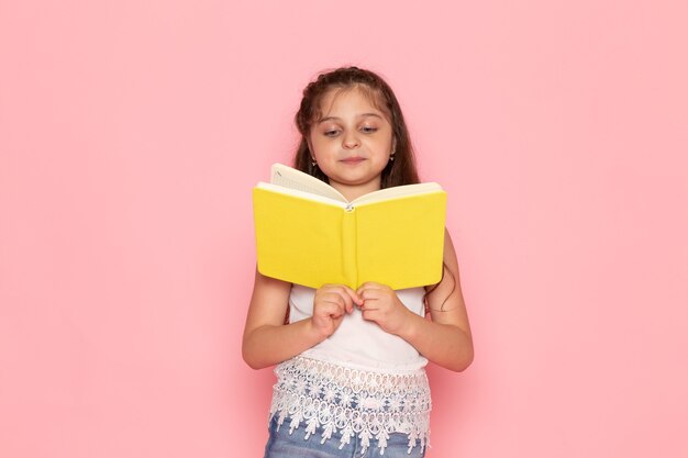 A front view cute little kid reading yellow copybook