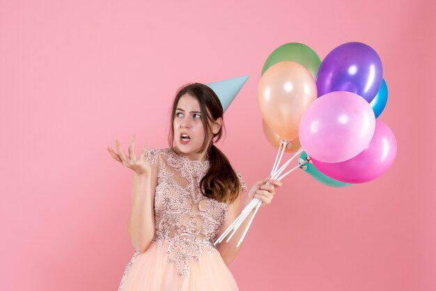 Front view cute party girl with party cap holding balloons something