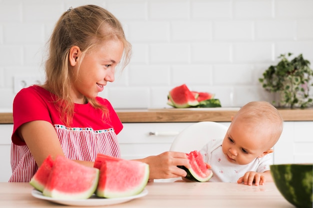 Front view of cute sisters eating watermelon