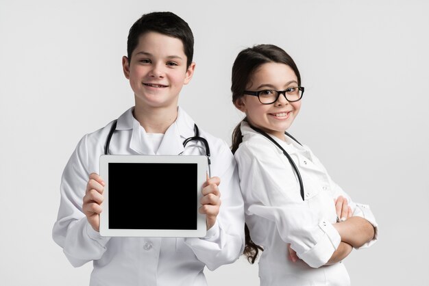 Front view cute young boy and girl posing as doctors