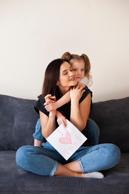 Front view cute young girl hugging her mother