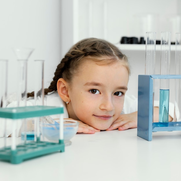 Free photo front view of cute young girl scientist with test tubes