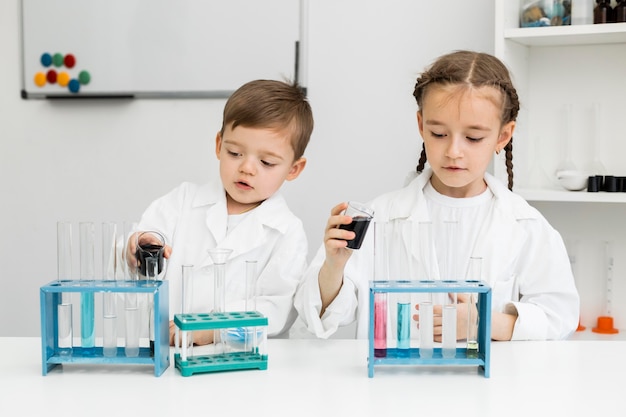 Front view of cute young kids scientists with test tubes in the laboratory