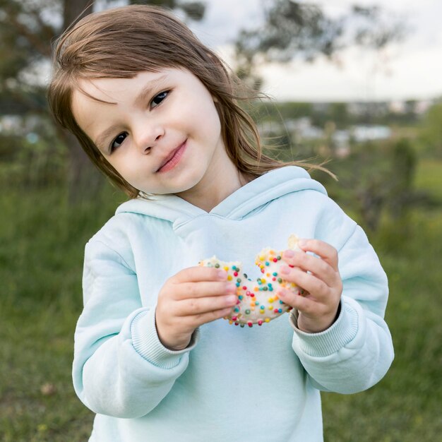 Front view cute youngster eating a doughnut