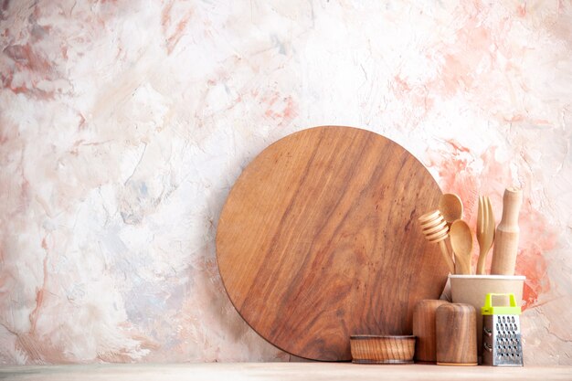 Front view of cutting board wooden spoons grater on colorful surface