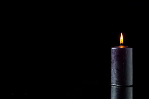 Front view of dark candle lighting on dark surface