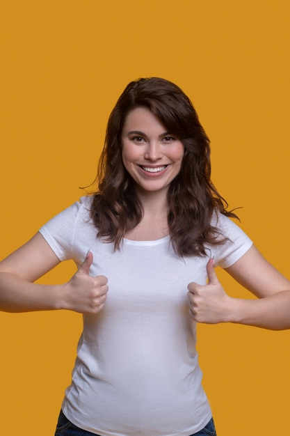 Front view of a dark-haired young woman with making a thumbs-up gesture before the camera