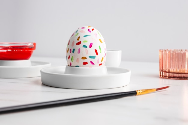 Front view of decorated easter egg on plate with paint and paintbrush