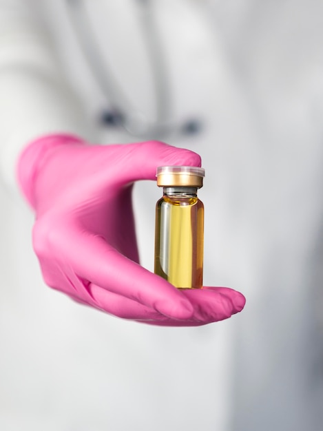 Free photo front view of defocused doctor with surgical glove holding vaccine