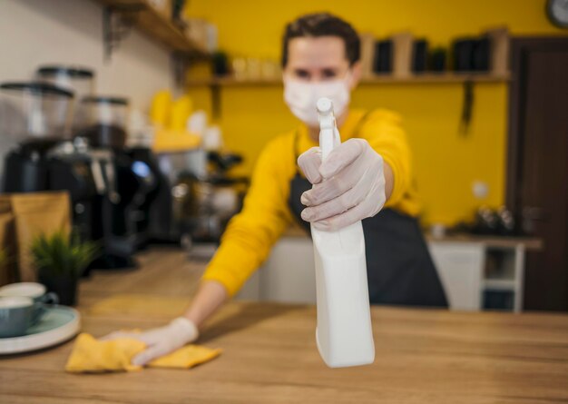 Front view of defocused female barista with medical mask