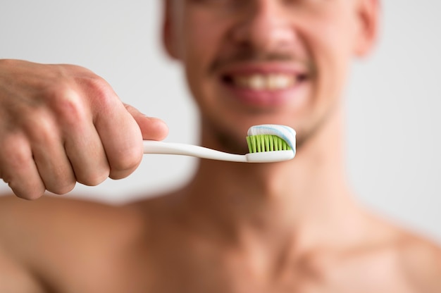その上に歯磨き粉と歯ブラシを保持している焦点がぼけた男の正面図