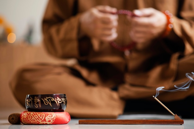 Vista frontale dell'uomo defocused meditando con perline accanto alla campana tibetana