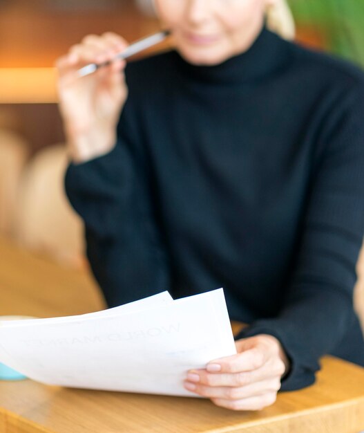 Front view of defocused older woman at work reading papers