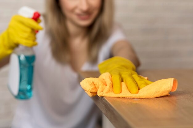 Front view of defocused woman cleaning surface with cloth