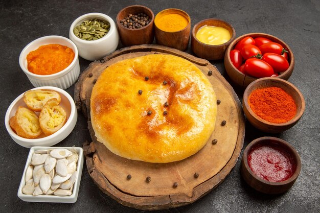 Front view delicious baked pie with seasonings on a dark-grey background pie cake bake dough ripe