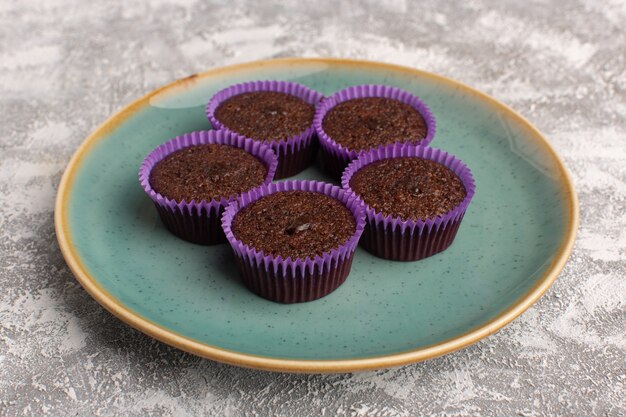 Front view of delicious brownies inside green plate on the light surface