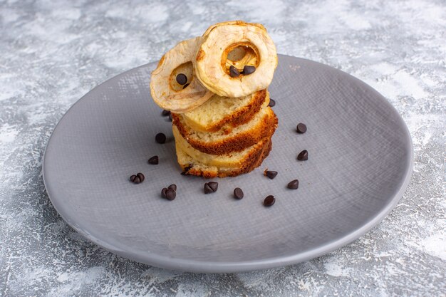 Front view of delicious cake slices inside plate with choco chips on grey-light desk