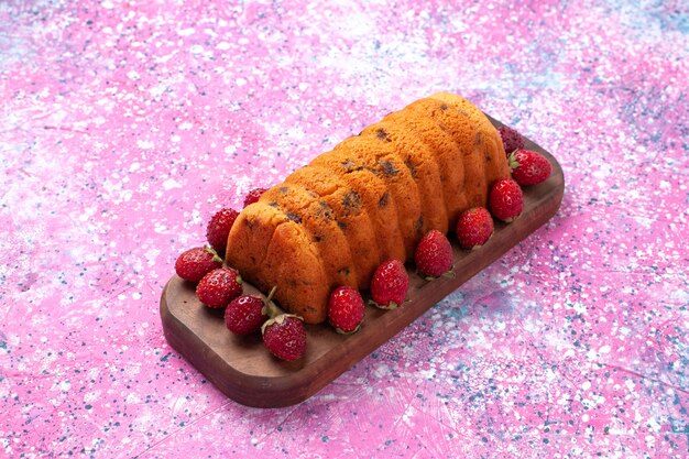Вкусный торт вид спереди с красной свежей клубникой на розовом столе.