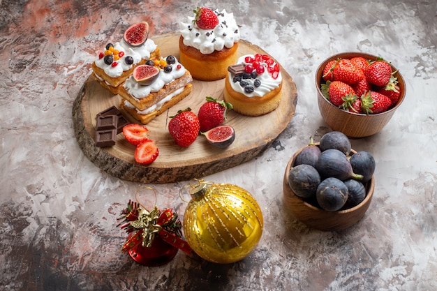 Free photo front view delicious cakes with fresh fruits on light background christmas cake dessert biscuit color