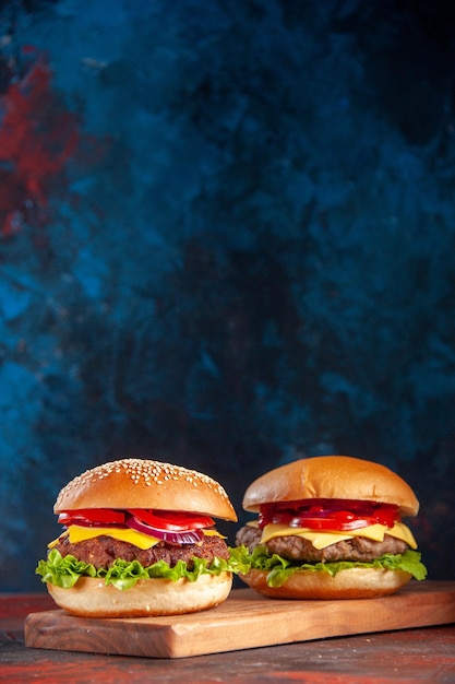 正面図暗い背景に肉トマトとグリーンサラダとおいしいチーズバーガーファーストフードの食事スナックフライドポテトディナーサンドイッチ Premium写真