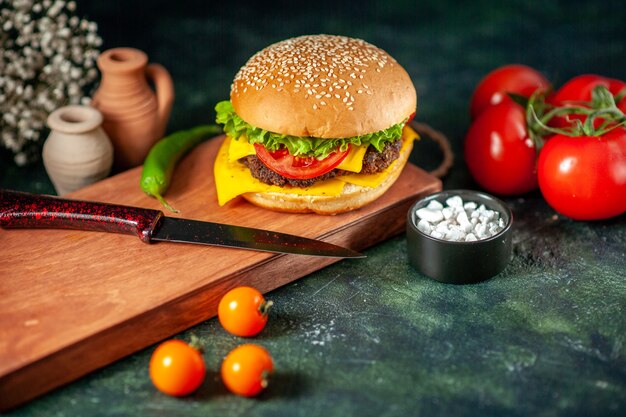 front view delicious cheeseburger with tomatoes on dark background