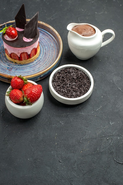 Vista frontale deliziosa cheesecake con fragole e cioccolato su ciotole con fragole al cioccolato