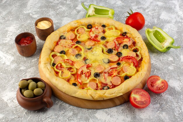 Front view of delicious cheesy pizza with olives sausages and tomatoes