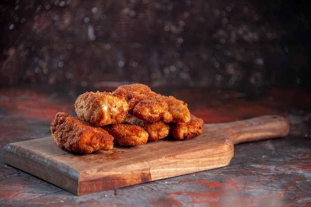 Вид спереди вкусные куриные крылышки на разделочной доске темный фон еда ужин еда картофель фри сэндвич обед мясной цвет
