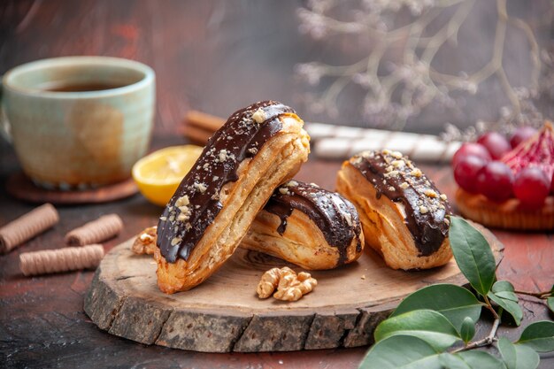 Front view delicious choco eclairs on dark background