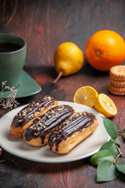 Front view delicious choco eclairs with tea on a dark background