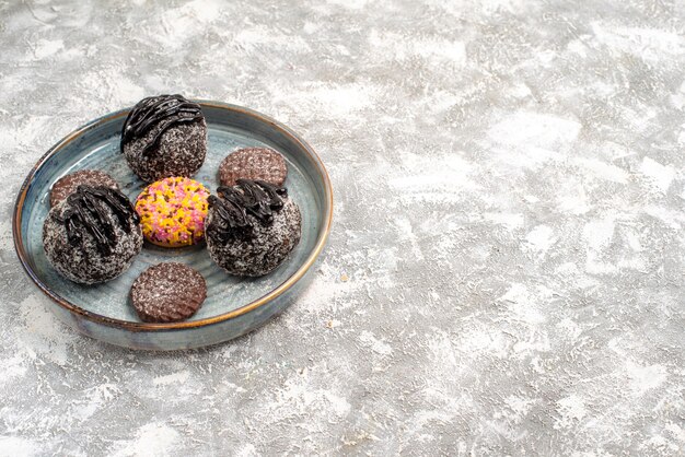 Вид спереди вкусные шоколадные шарики, торты с печеньем на светлом белом пространстве
