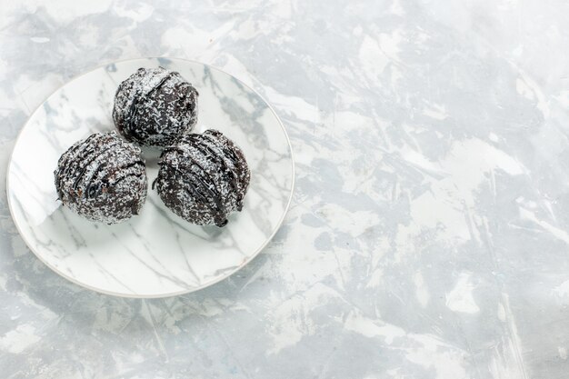 Front view delicious chocolate balls round formed cakes with icing on light white desk bake cake chocolate sugar pie sweet