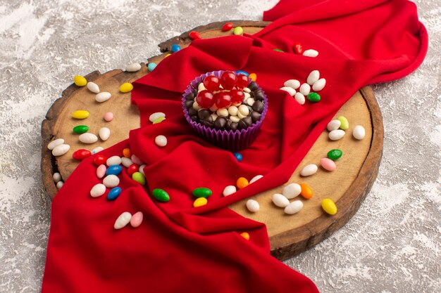 Front view of delicious chocolate brownie with colorful candies on the light surface