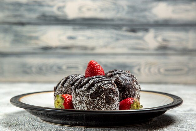 Front view delicious chocolate cakes with fresh red strawberries on the white surface chocolate sugar biscuit sweet cake bake cookies