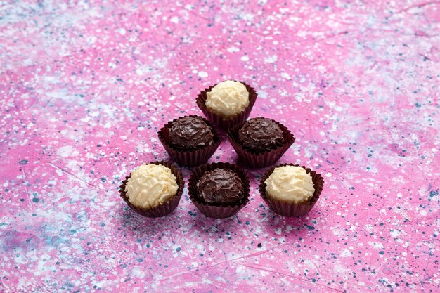 전면보기 맛있는 초콜릿 사탕 분홍색 배경에 흰색과 어두운 초콜릿.