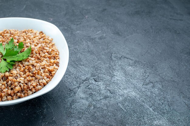 Front view delicious cooked buckwheat useful meal inside plate on a dark space