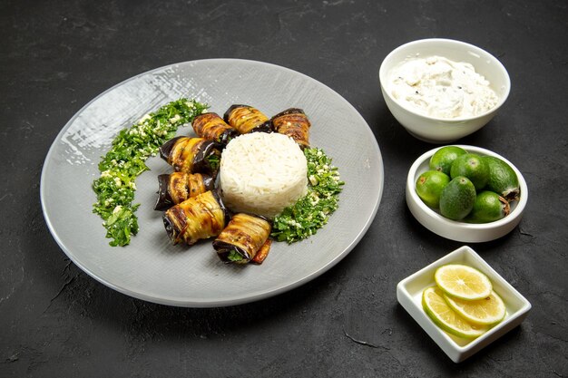 Front view delicious cooked eggplants with rice lemon and feijoa on dark surface dinner food cooking oil rice meal