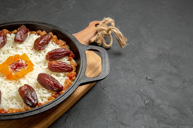 Front view delicious cooked plov rice meal with khurma and raisins on grey surface plov rice dish meal cooking