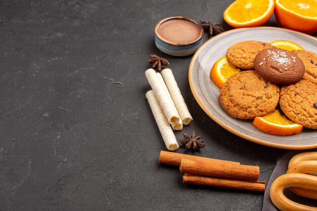 Front view delicious cookies with fresh sliced oranges on dark desk sugar cookie fruit biscuit sweet