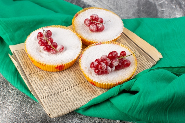 Free photo front view of delicious cranberry cakes with red cranberries on top sugar pieces and powder
